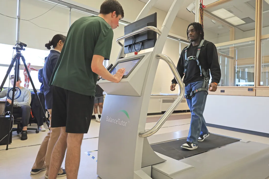 A student researcher examines a student athlete on a BalanceTutor machine