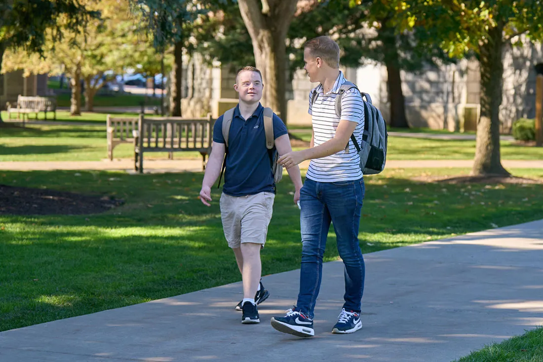 Two brothers walking down sidewalk on campus