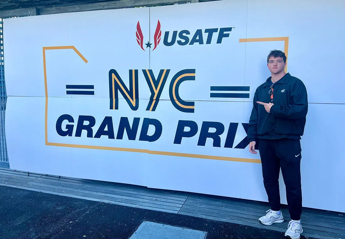 student standing in front of banner that reads NYC Grand Prix