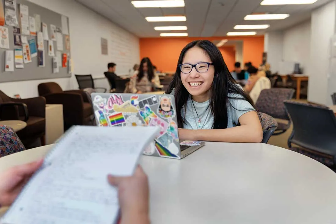 student looking at laptop while sitting in student lounge