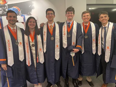 six scholars standing together in cap and gowns
