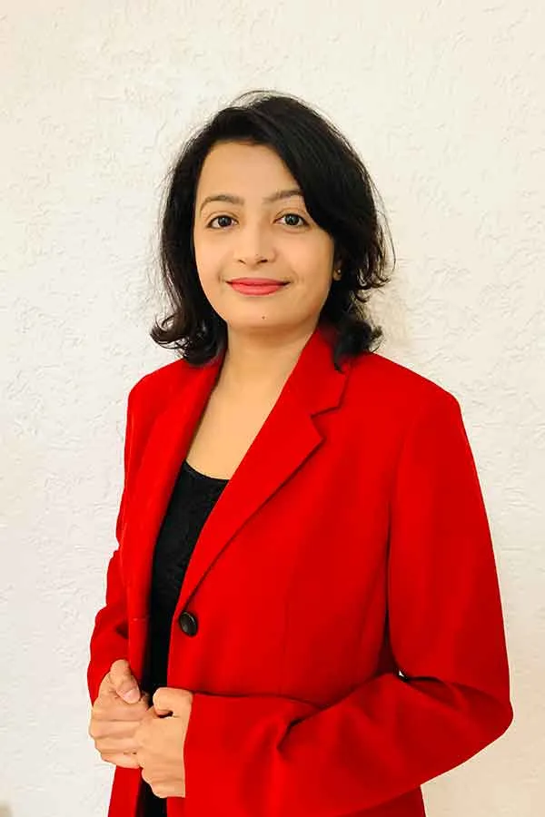 women with shoulder length dark hair and wearing a red jacket over a black shirt is smiling