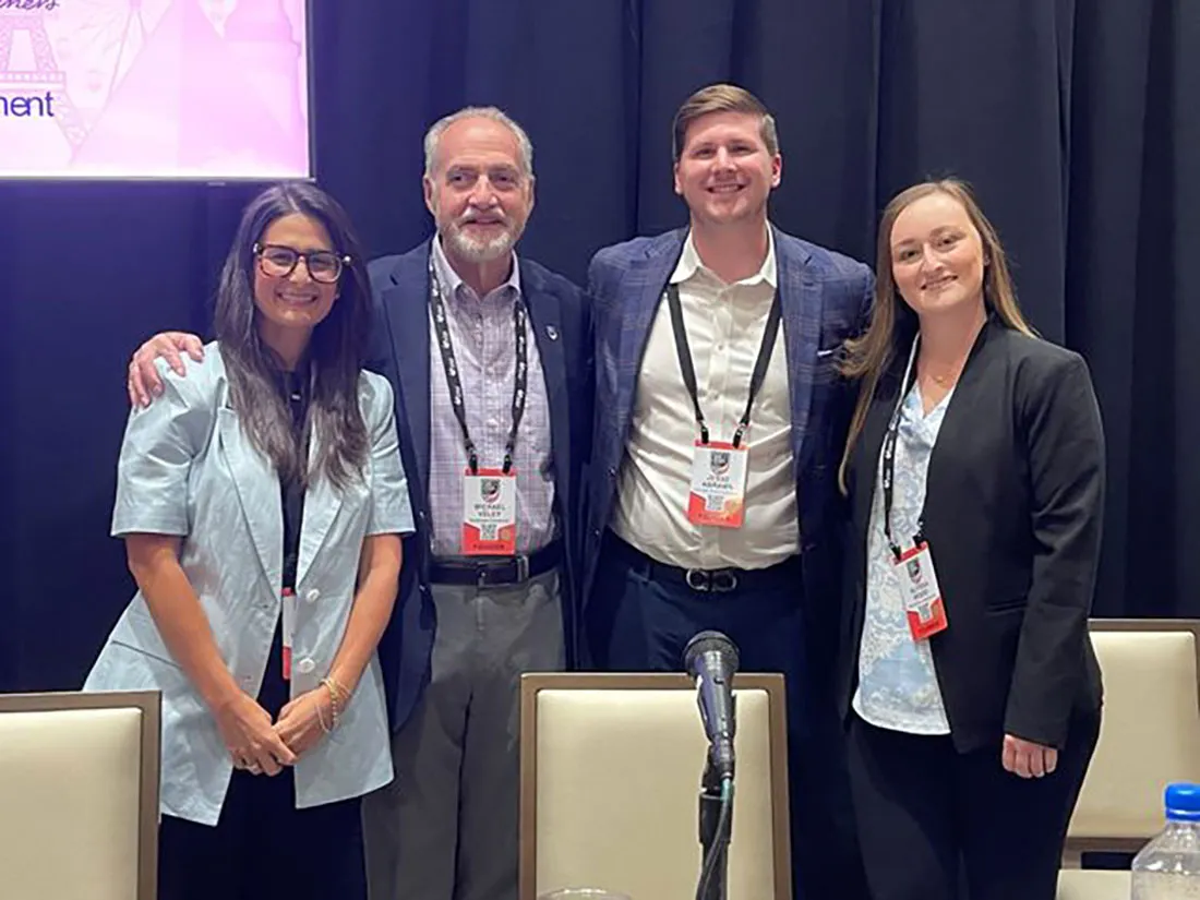 three alumni stand with professor