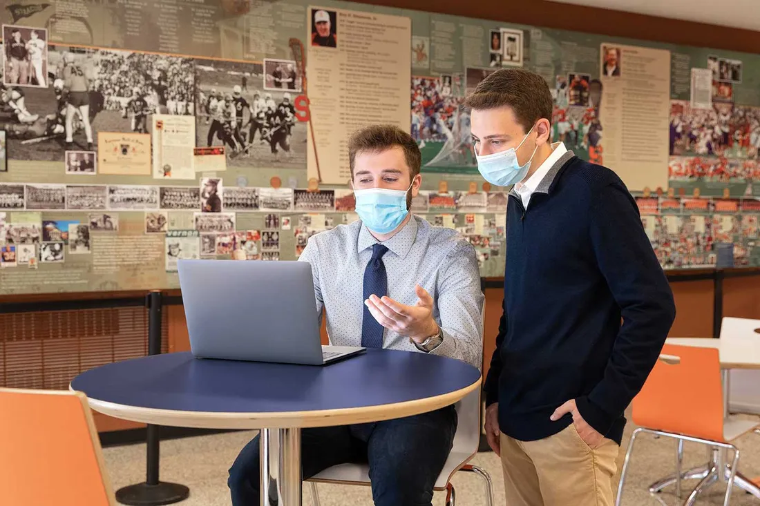 two students around a table looking at computer screen