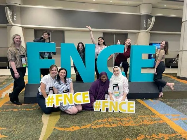 ten students gathered around FNCE letters on platform