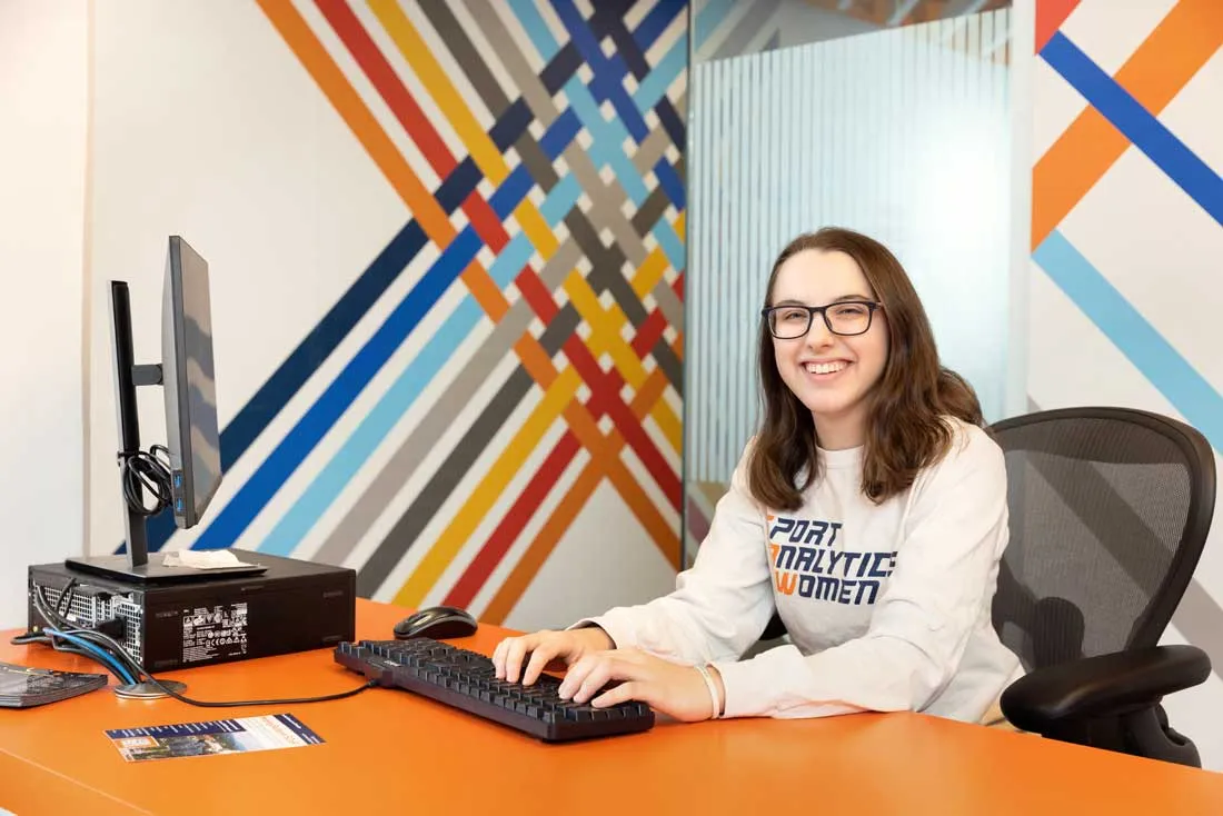 student sitting behind desk with her hands on a keyboard