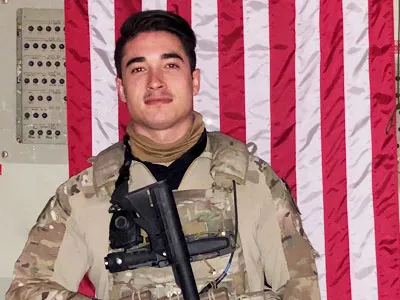 student veteran in uniform standing in front of american flag