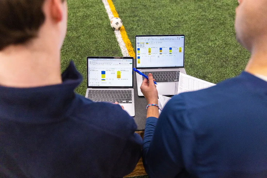 Two analytics students compare data on the field