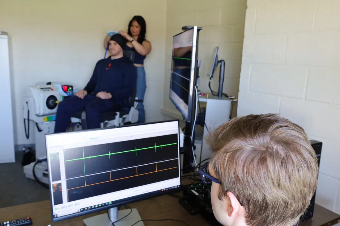 A student examines an athlete with brain scanning equipment