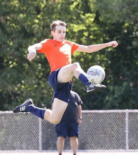 Gavin Anderson jumping in the air to kick a soccer ball
