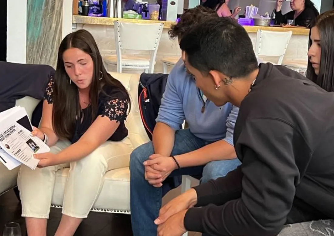 3 students sitting on the couch looking at a paper