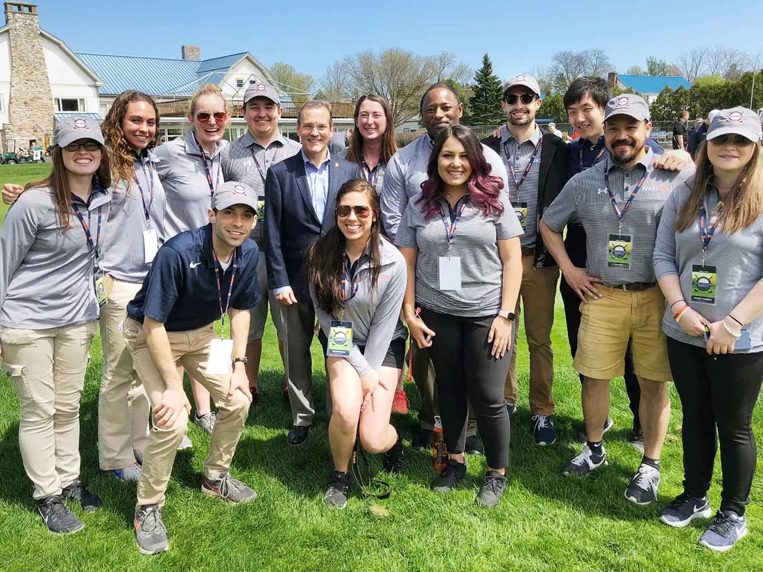 on the grass event management students and faculty gather together