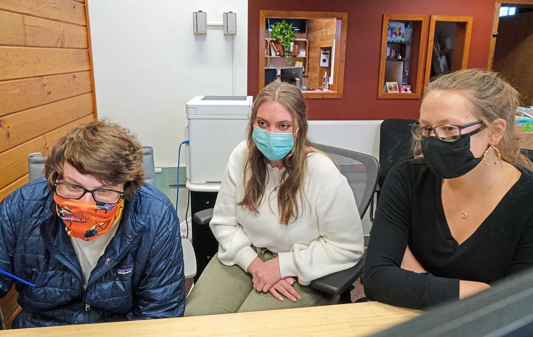 3 students sitting at table wearing masks because of COVID