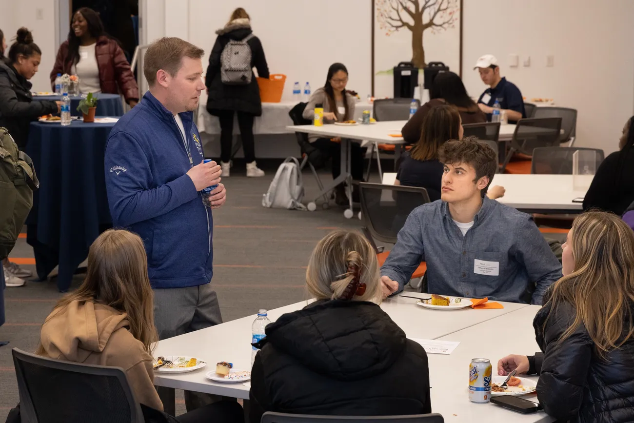 An alum engages with a table of students during a networking event
