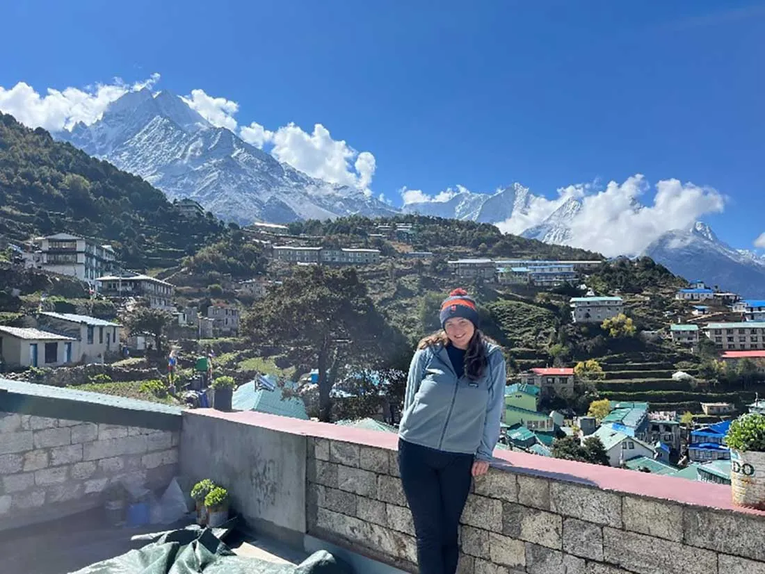 student in winter clothing standing on brick balcony overlooking the mountains and city