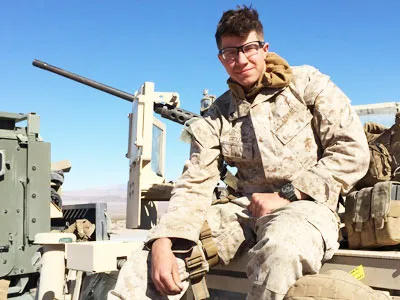 student veteran in military clothes sitting on a tank