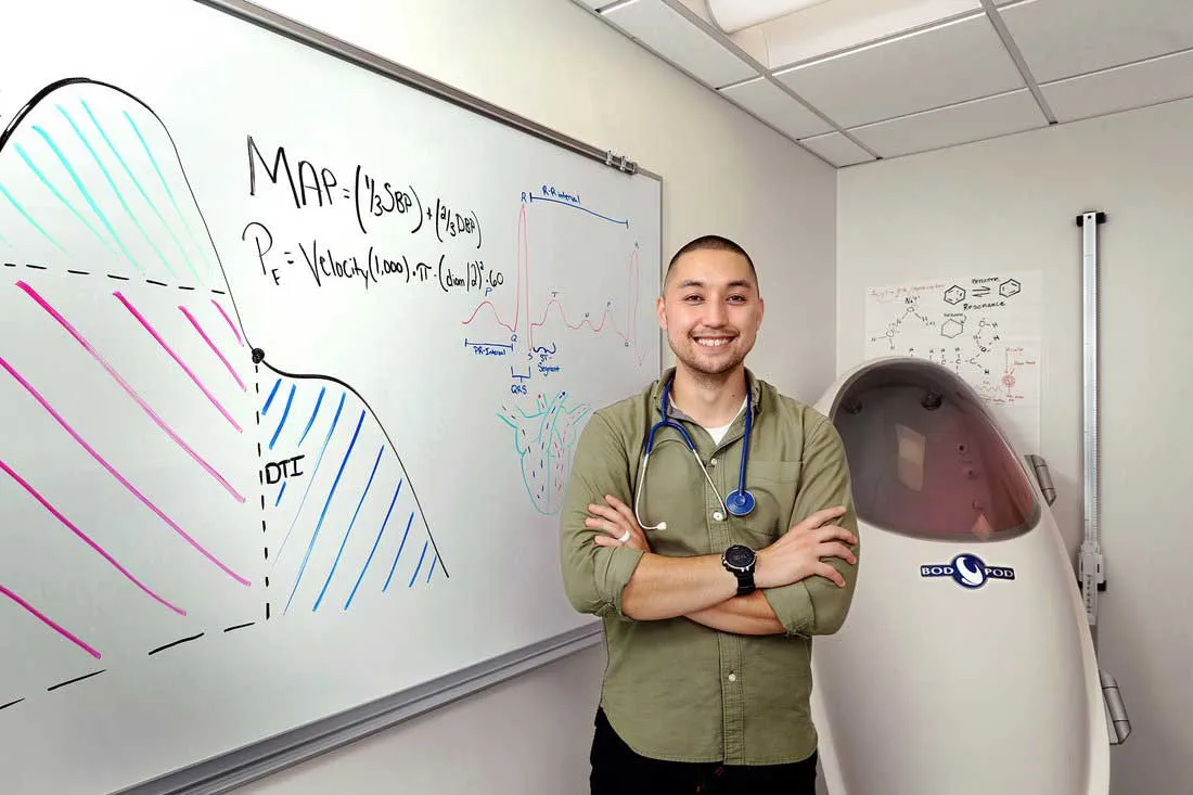 young man standing in front a white board with diagrams written on it