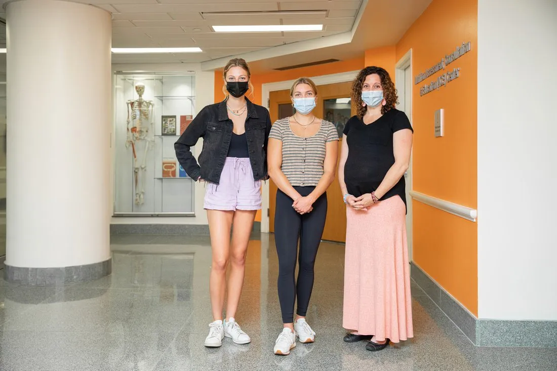 two students and one professor standing in hallway