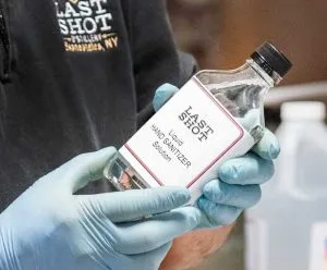 gloved hands holding glass bottle