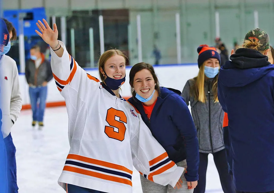 group of people including two young women on hockey ice
