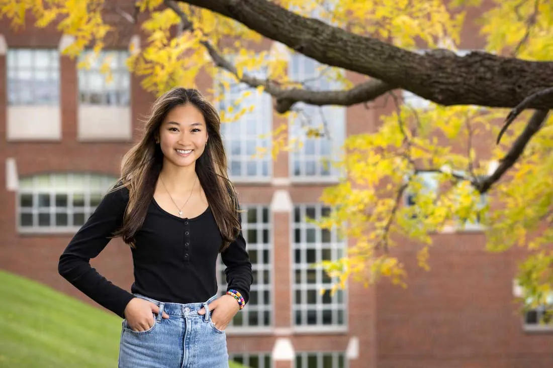 A female student stands in front of Falk College