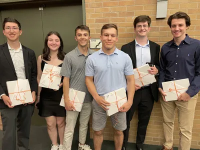 six sport analytics students standing in front of brick building