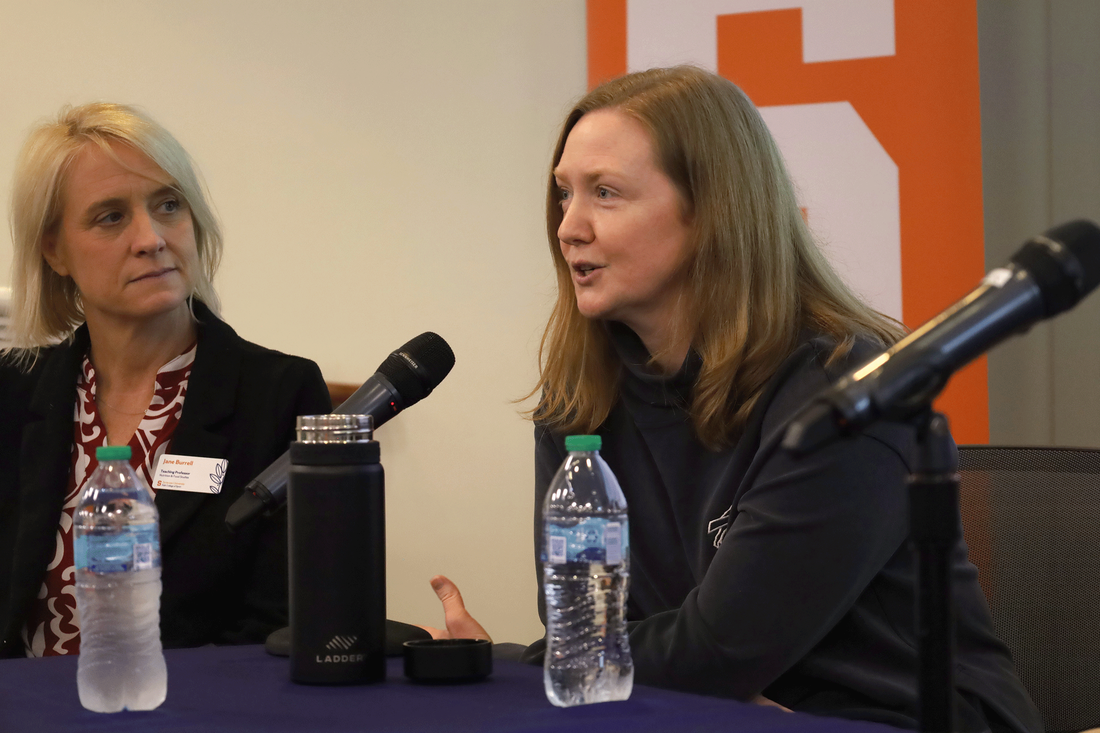 Christine Diedzic sitting at table as part of panelist for lecture series